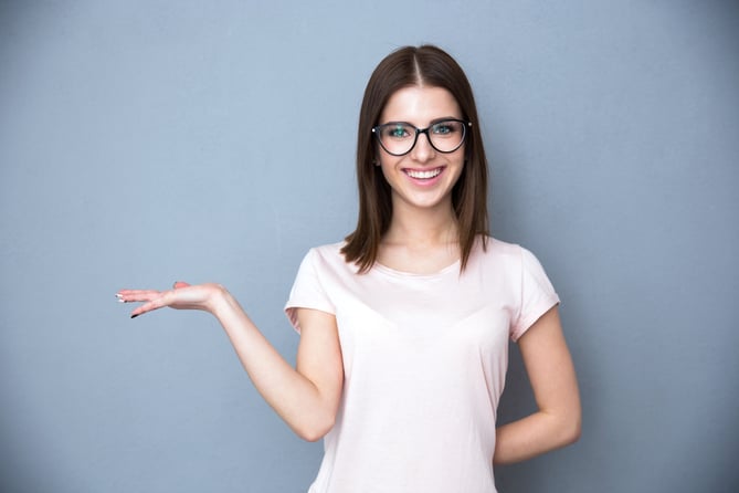 Happy young woman in glasses presenting something on the hand