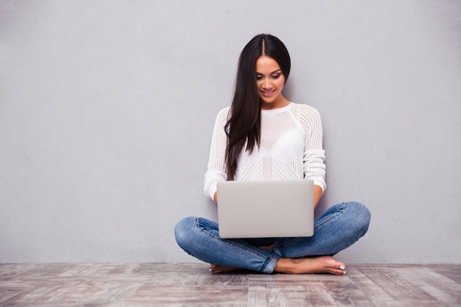 Femme assise contre le mur et étant sur son ordinateur